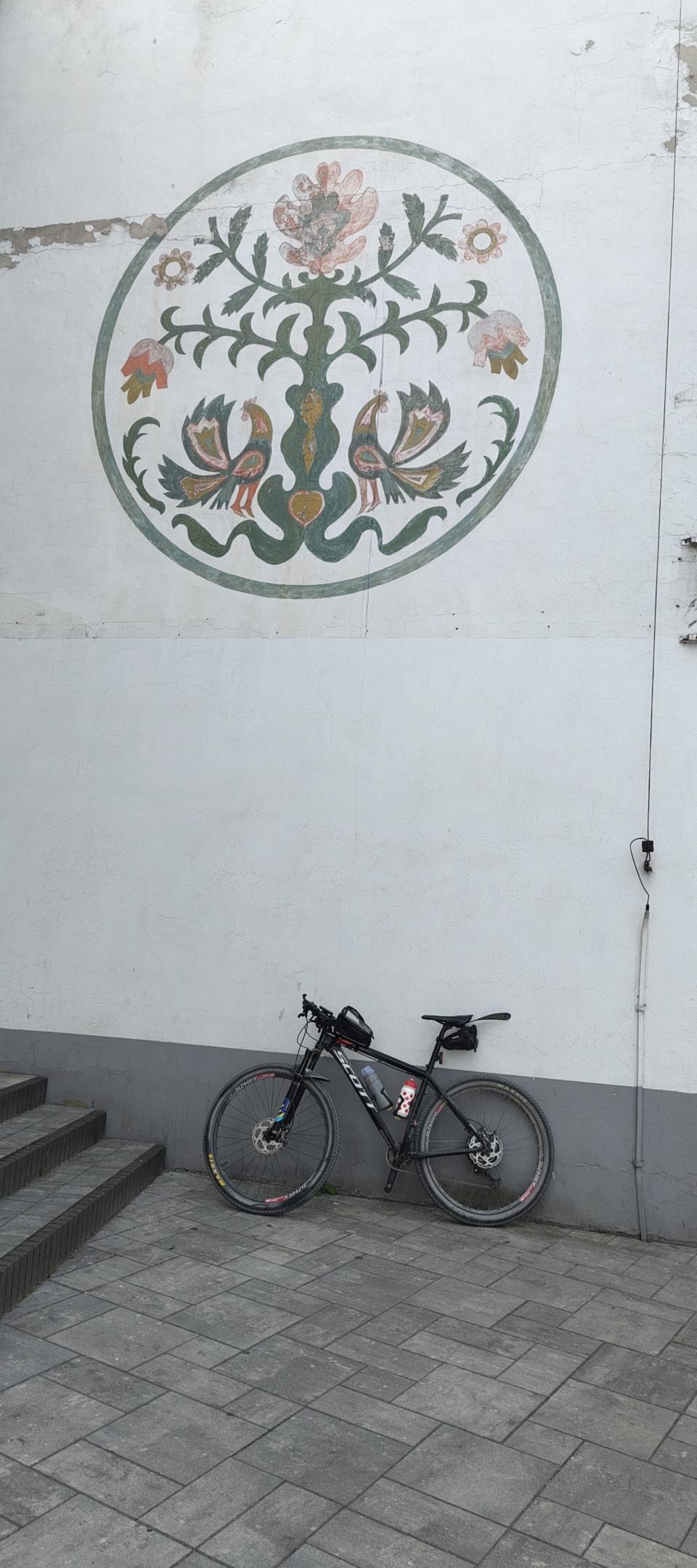 Rower oparty o ścianę, na ścianie mural z łowickim wzorem
