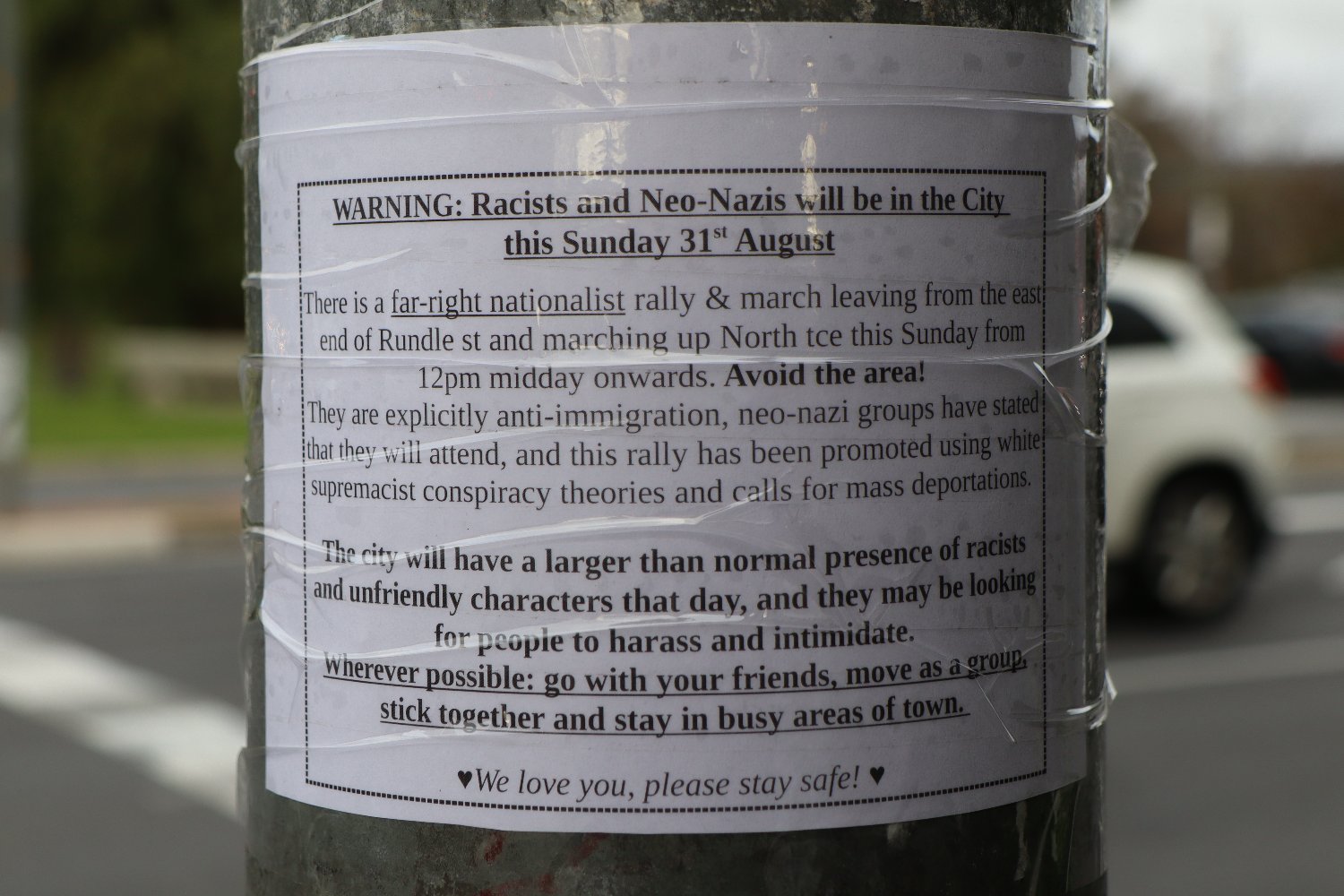 Sign sticky taped to pole warning residents of racist and nazi rally in the area. 