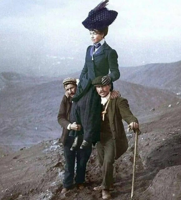 A lady carried by two men in suits